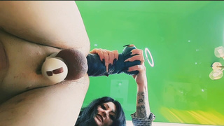 Bottom view, slave in chastity belt takes monstrous toys into his hole.